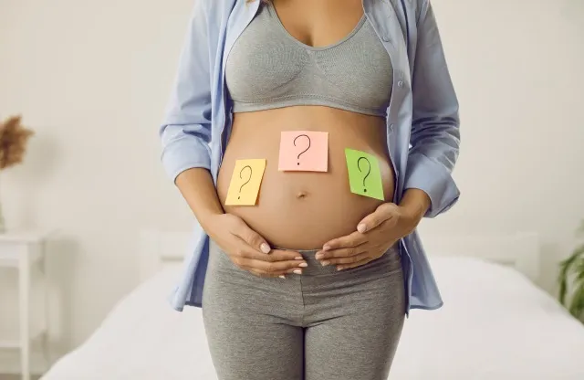 将来の赤ちゃんの名前を考えているお母さん。 胎児の性別を当てようとしている女性。 大きなむき出しの腹にクエスチョン マークの付箋を付けた妊娠中の女性、クロップド ショット。 名前の選択、性別明らかにコンセプト
